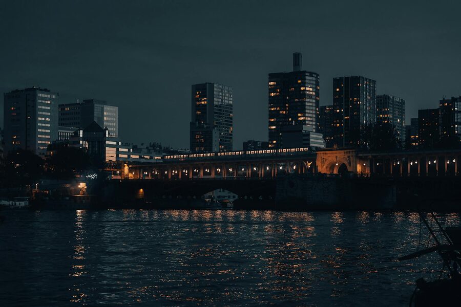 Nighttime view of Paris skyline with illuminated buildings reflected on the Seine River