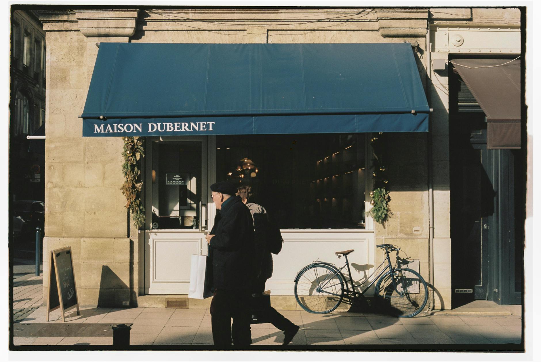 Sunny street view of Maison Dubernet in Bordeaux with people walking by