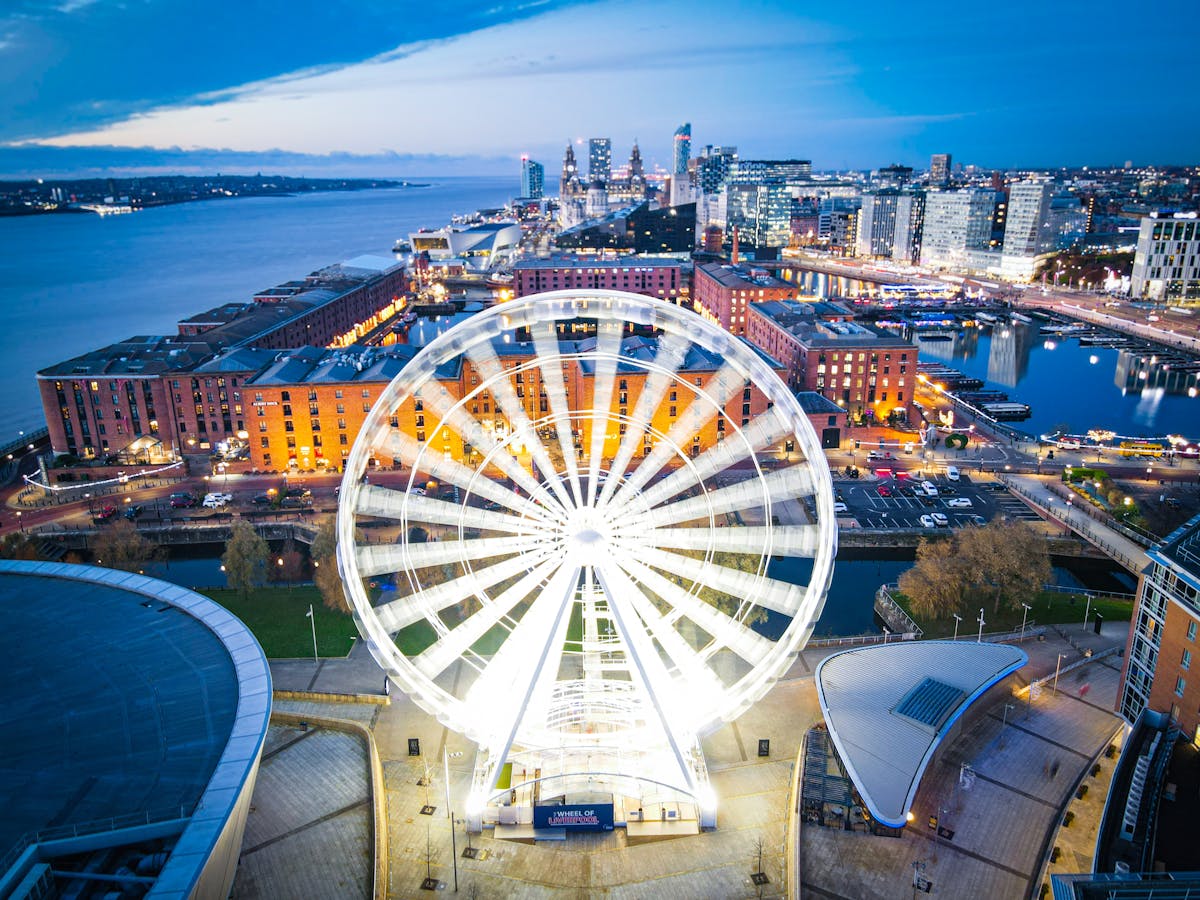 The illuminated Wheel of Liverpool at the waterfront with city skyline in the evening