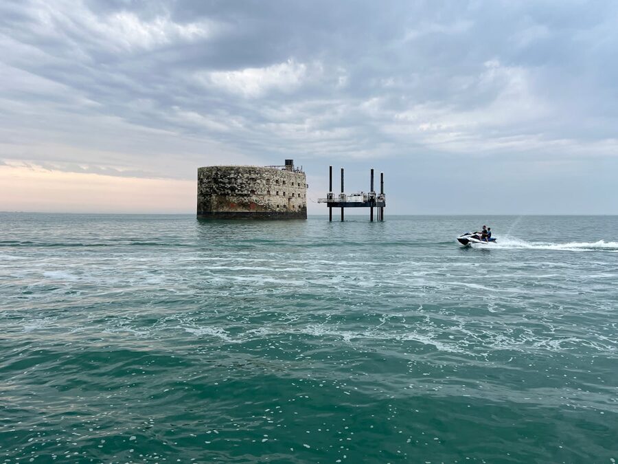 Jet ski passes by Fort Boyard in Fouras France under dramatic cloudy skies