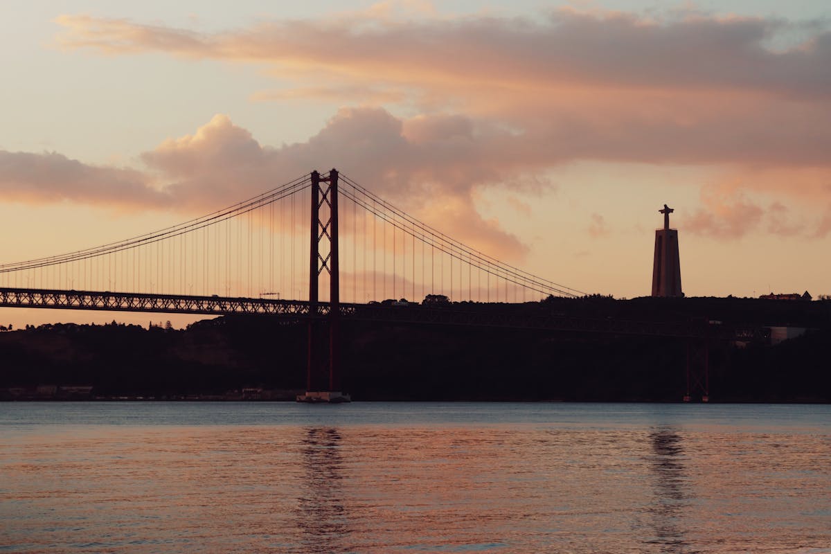 The 25 de Abril Bridge and Cristo Rei statue at sunset in Lisbon, Portugal