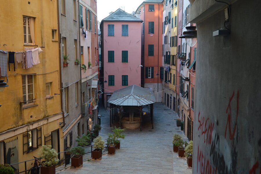 A narrow alley in the historic centre of Genoa with colourful buildings and hanging laundry