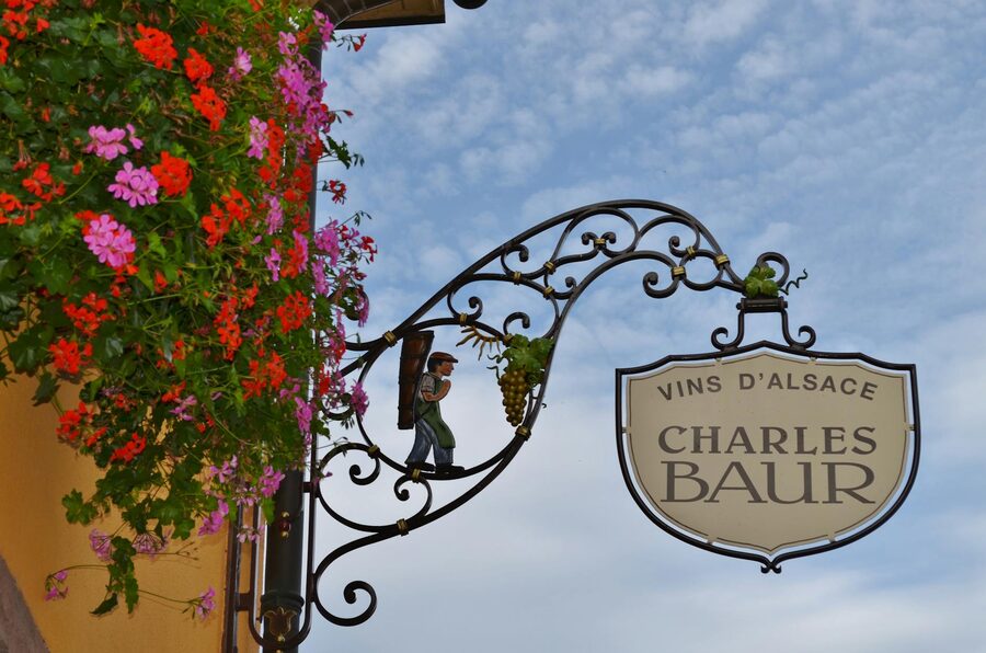 Decorative wrought-iron wine shop sign with flowers in an Alsatian village