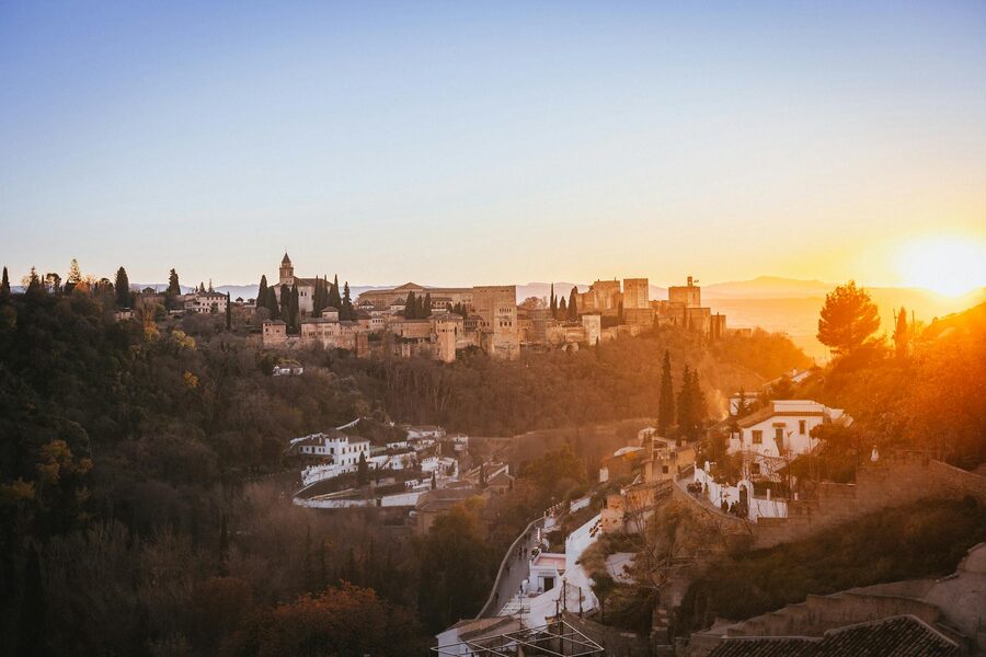 The Alhambra palace glowing in golden sunset light with Sierra Nevada mountains behind
