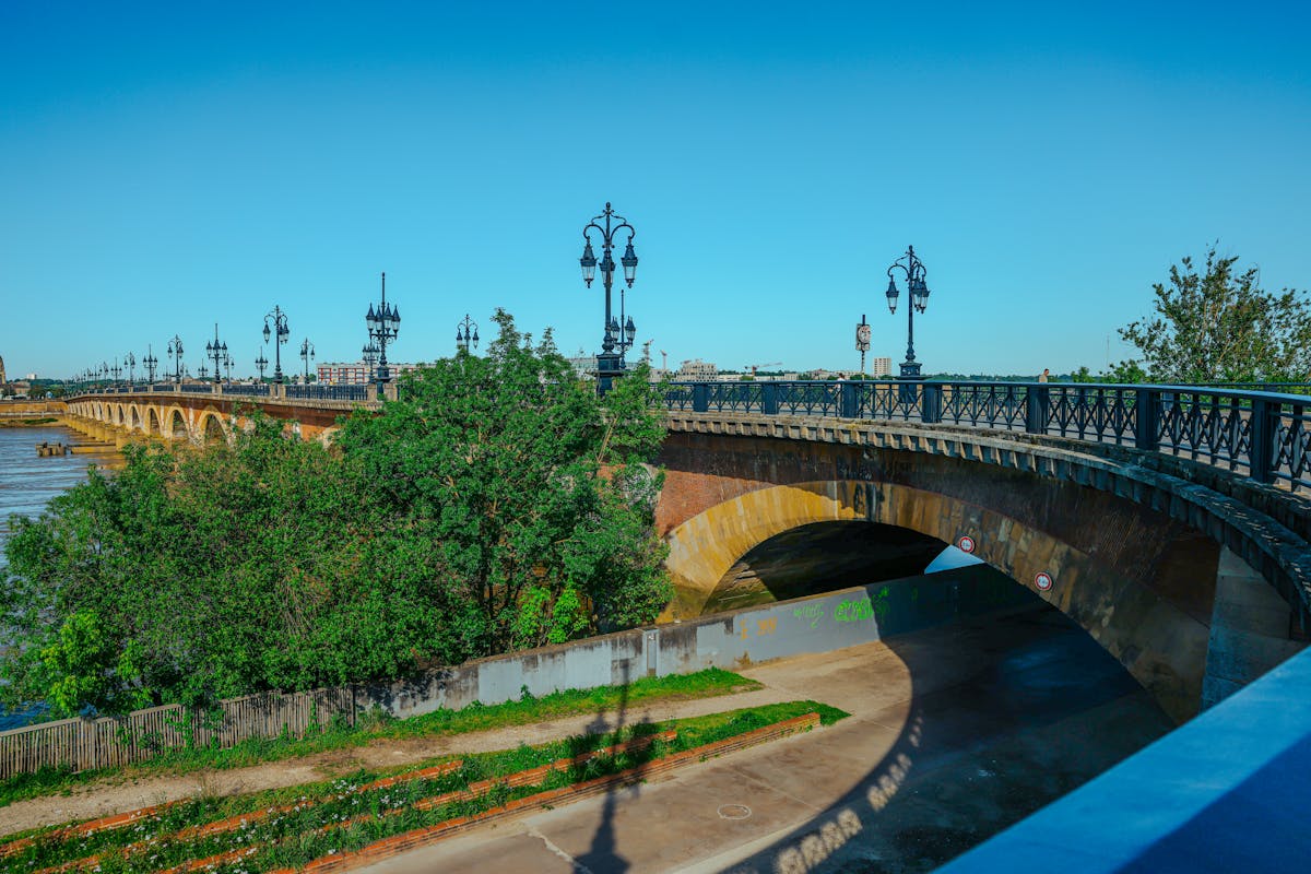 The Pont de Pierre stone bridge crossing the Garonne River in Bordeaux with blue skies