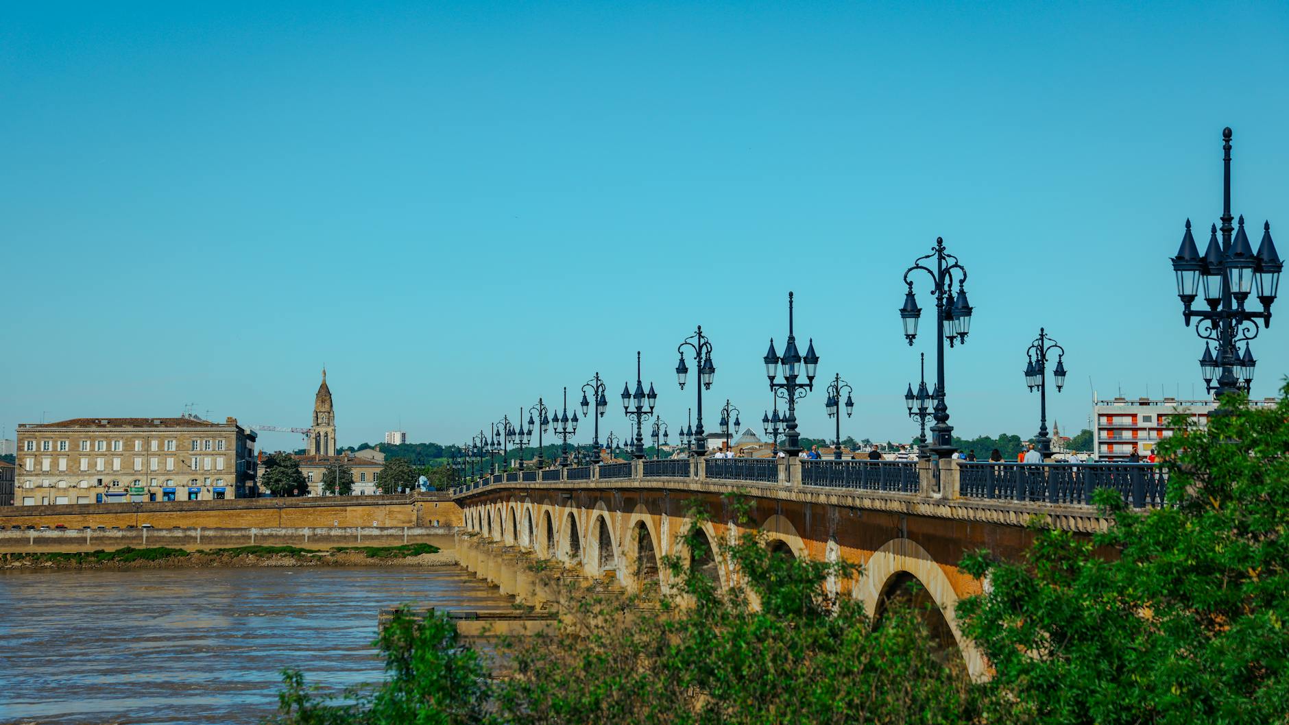 Pont de Pierre stone bridge spanning the Garonne River in Bordeaux on a clear sunny day