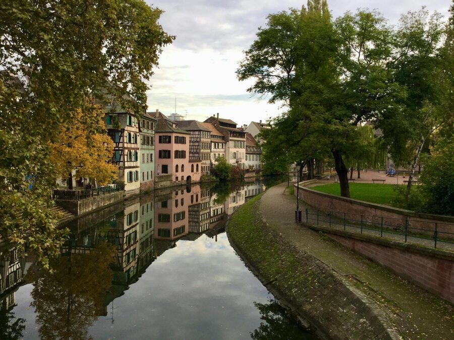 Scenic view of a Strasbourg canal with half-timbered houses and flower boxes reflecting in the water