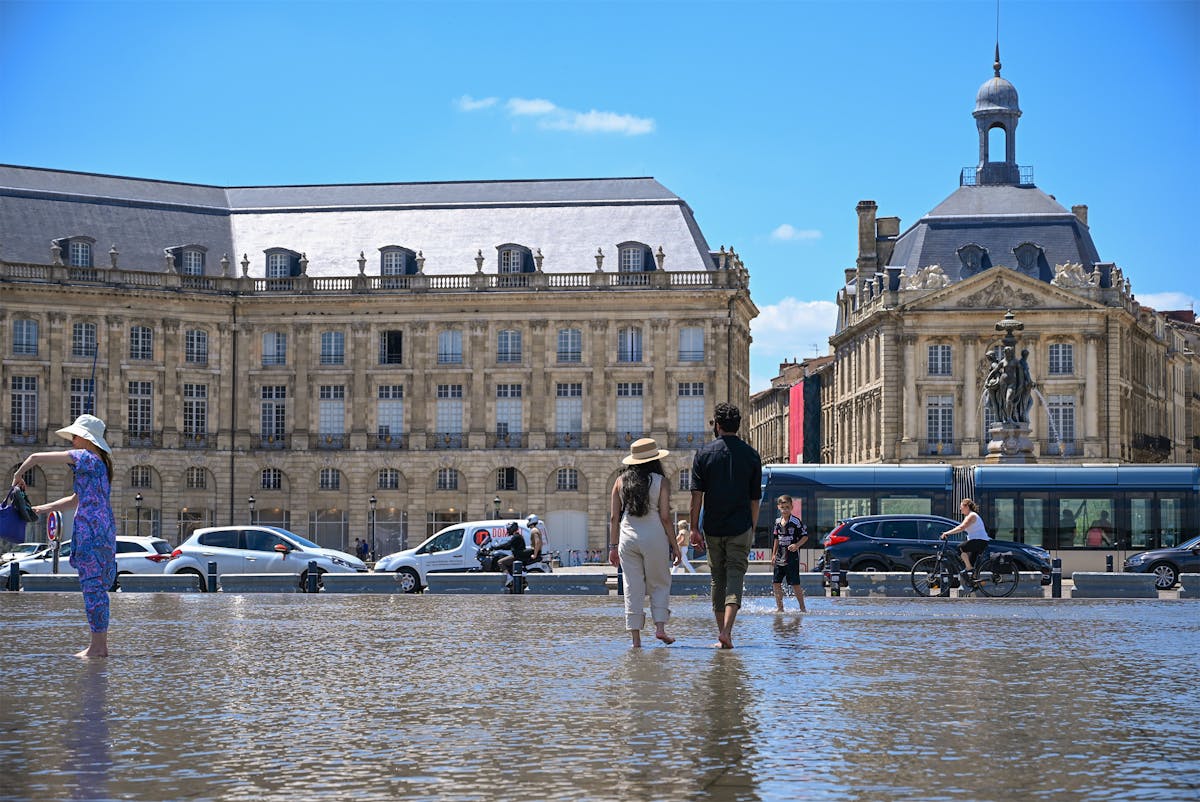 Visitors playing in the Miroir d Eau water mirror at Place de la Bourse Bordeaux on a sunny day
