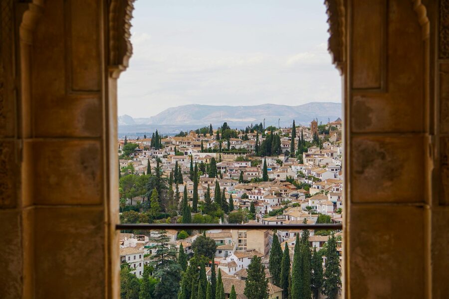 View of the city of Granada framed through a Moorish stone arch at the Alhambra