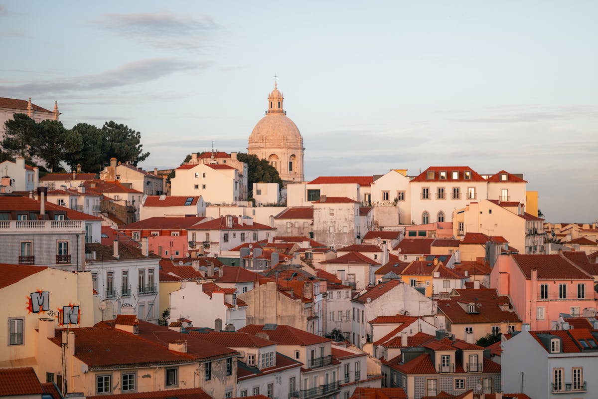 Lisbon Alfama district with traditional buildings and a dome under sunset sky