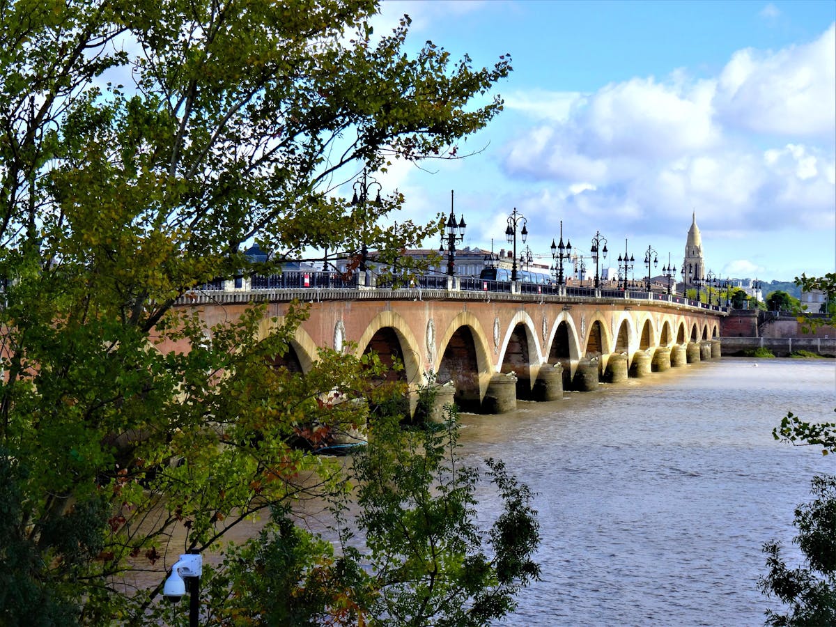 The Pont de Pierre stone bridge crossing the Garonne River in Bordeaux with clouds overhead