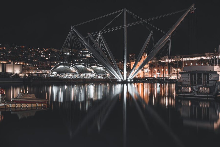 The Bigo crane structure and Porto Antico waterfront reflected in the harbour waters at night in Genoa