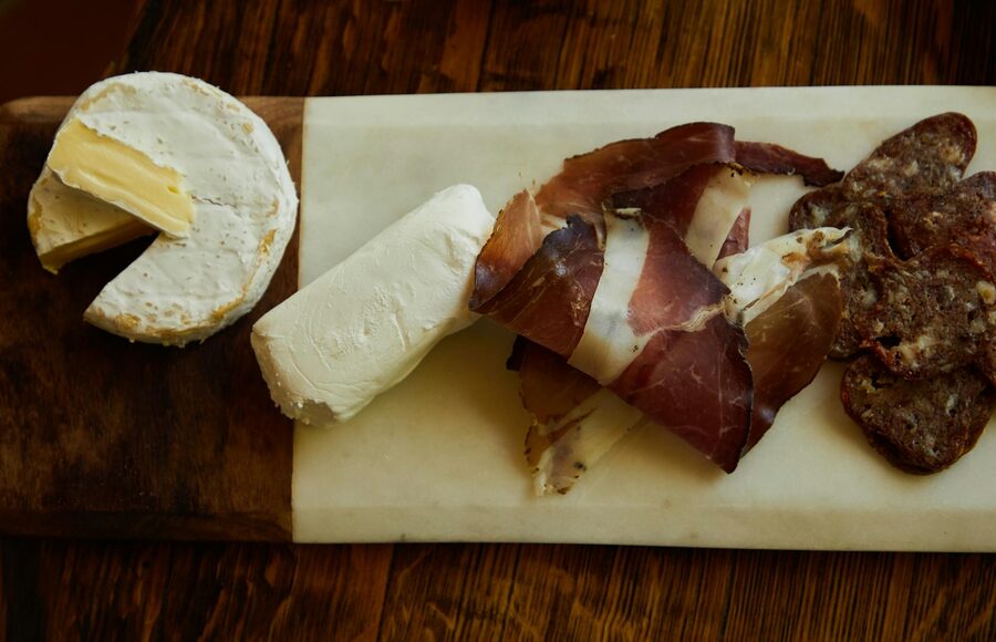 Overhead shot of a charcuterie board with various cheeses meats and accompaniments