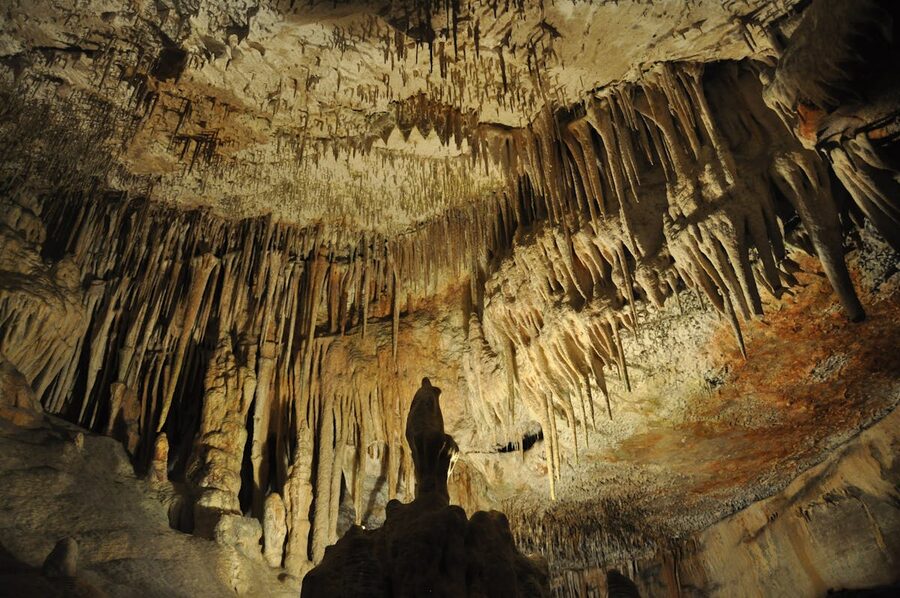 Stalactite formations lit with colored lights inside a Spanish cave system