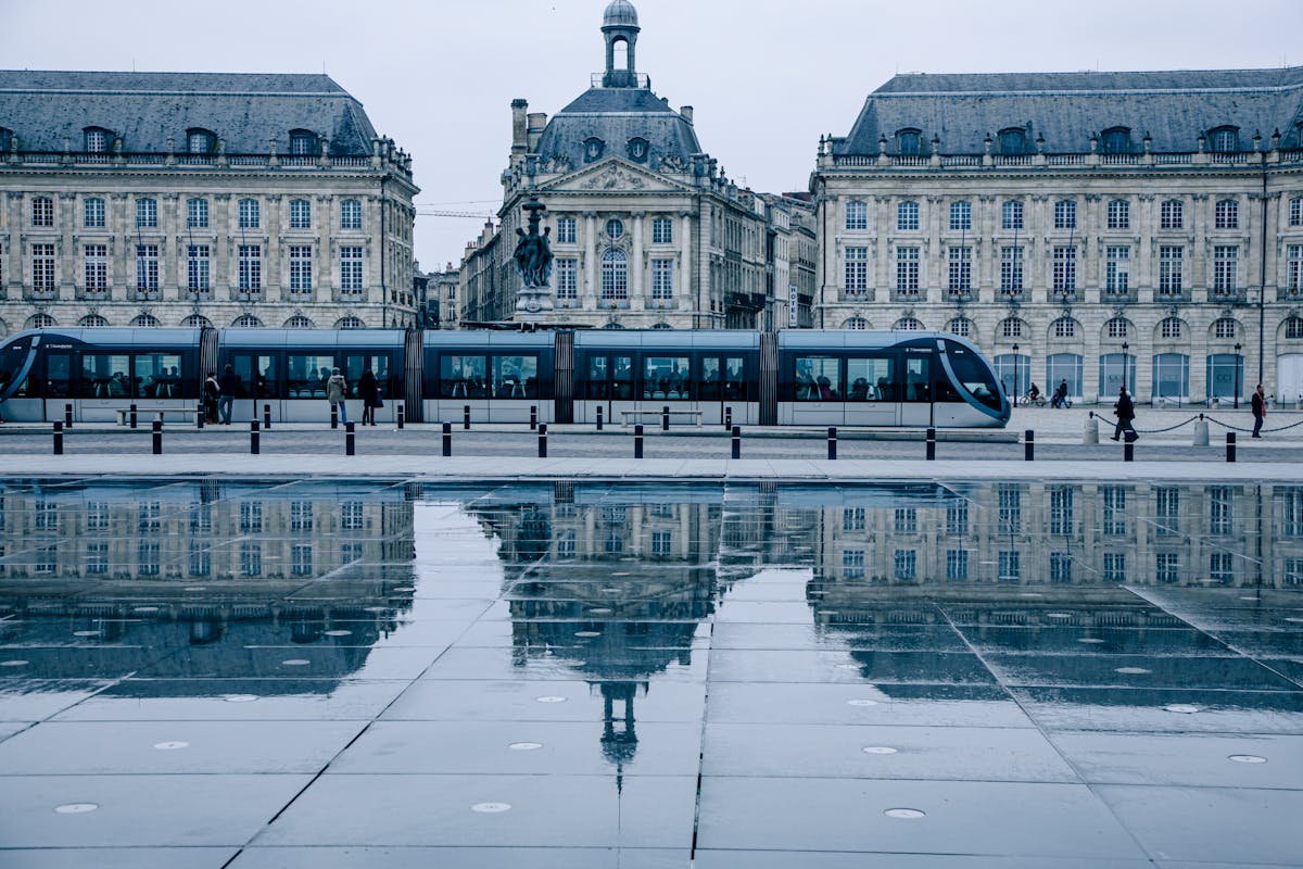 A tram passes in front of the historic Place de la Bourse reflecting in the Miroir d Eau in Bordeaux