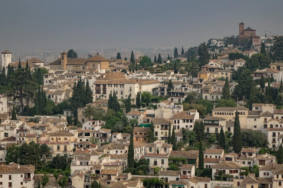 Wide panoramic view across the Albaicin district with traditional white houses and green hills