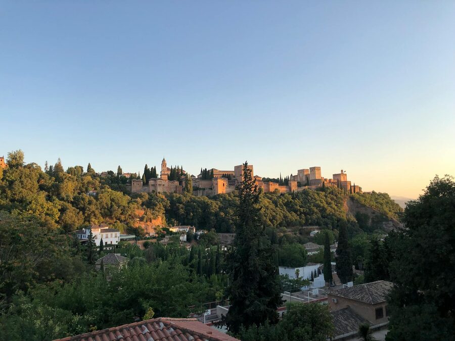 The Alhambra palace complex among lush trees with warm sunset light