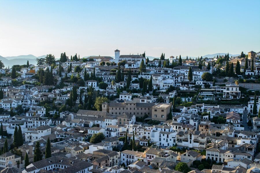 Green cypress trees rising above traditional Mediterranean architecture in Granada Spain