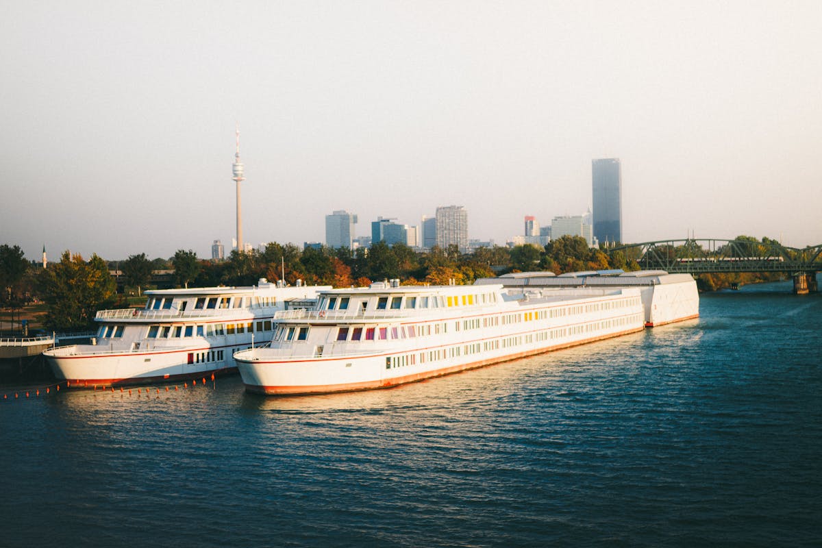 Several boats docked along the Danube River in Vienna with the city skyline in the background