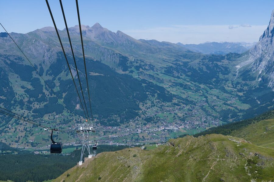 Aerial view from a cable car looking down at Grindelwald village and surrounding Swiss Alps