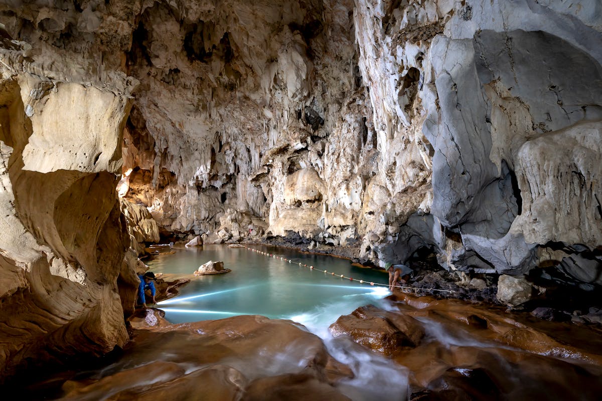 Crystal clear underground lake inside a limestone cave with stalactites