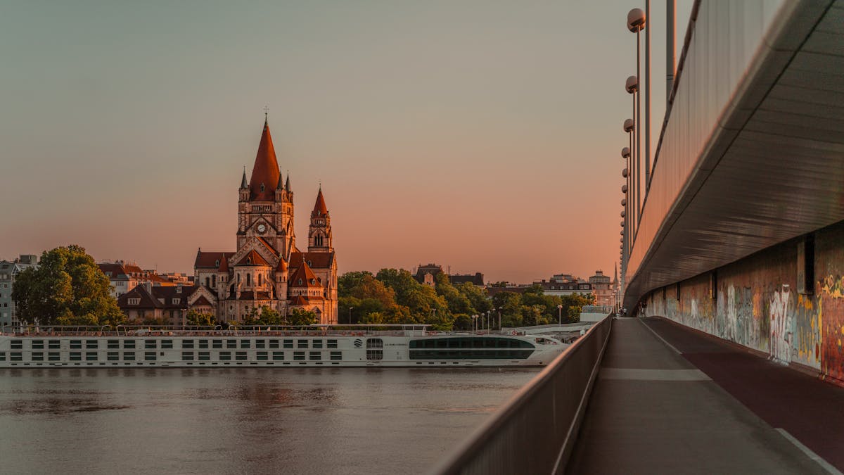 Sunset view of St. Francis of Assisi Church in Vienna with a river cruise boat on the Danube