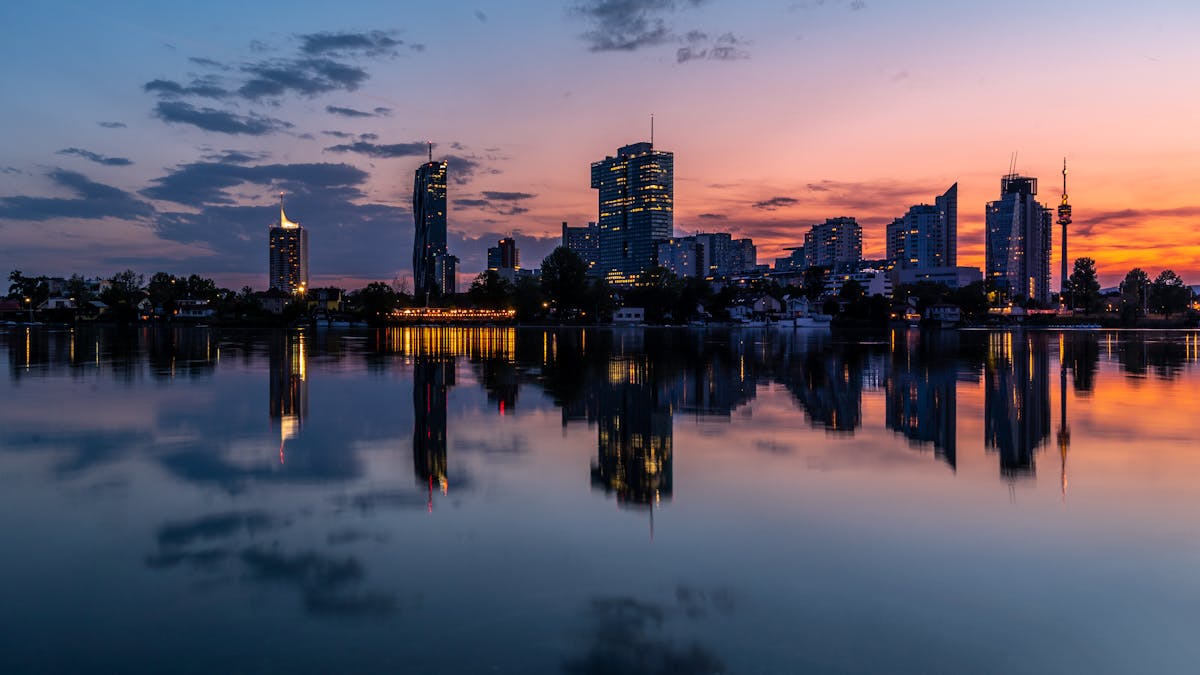 Tranquil reflection of Vienna cityscape at sunset with warm colors in the sky and water