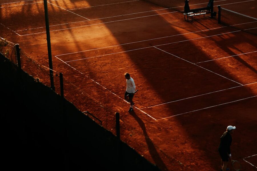 Aerial view of clay tennis court with red brick dust surface at golden hour