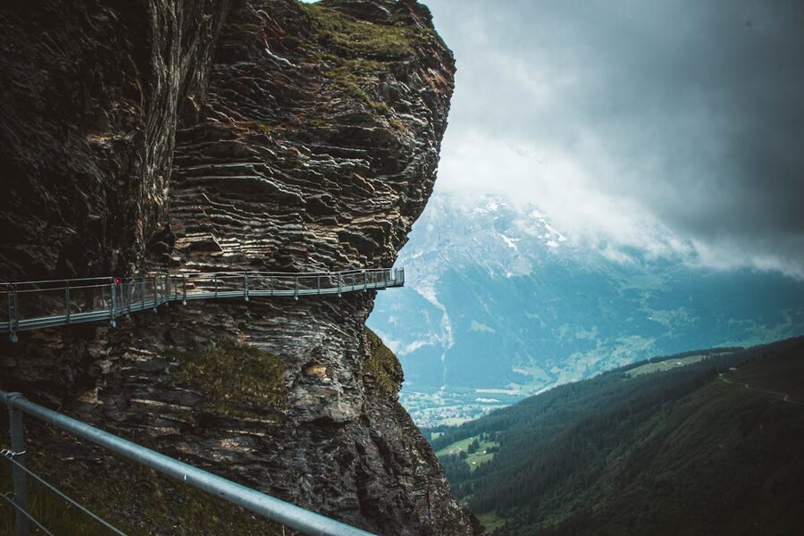Narrow walking path along a cliff face with dramatic Swiss Alpine views