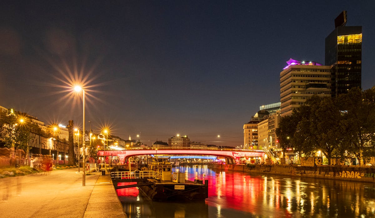 Scenic evening view of the Donaukanal in Vienna with illuminated buildings reflecting on the water