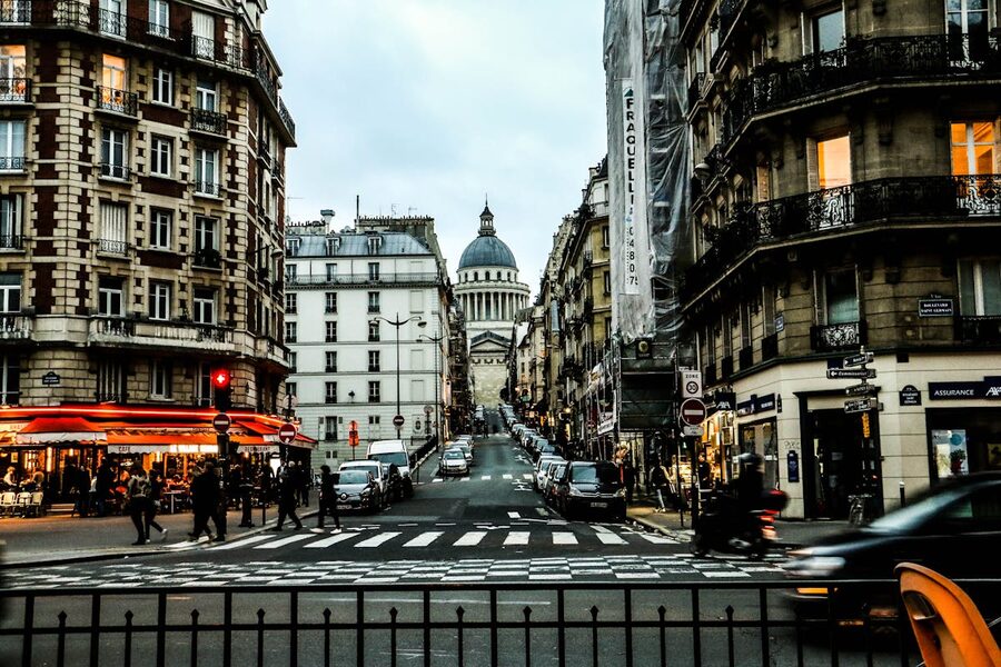 People crossing a street in the evening near historic European buildings