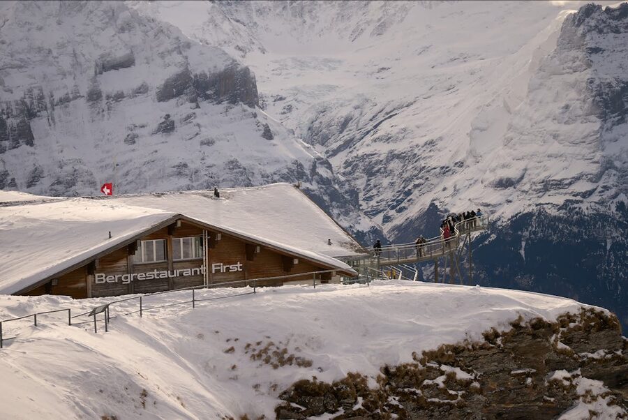 Mountain restaurant at First summit with snow-covered Swiss Alps in the background