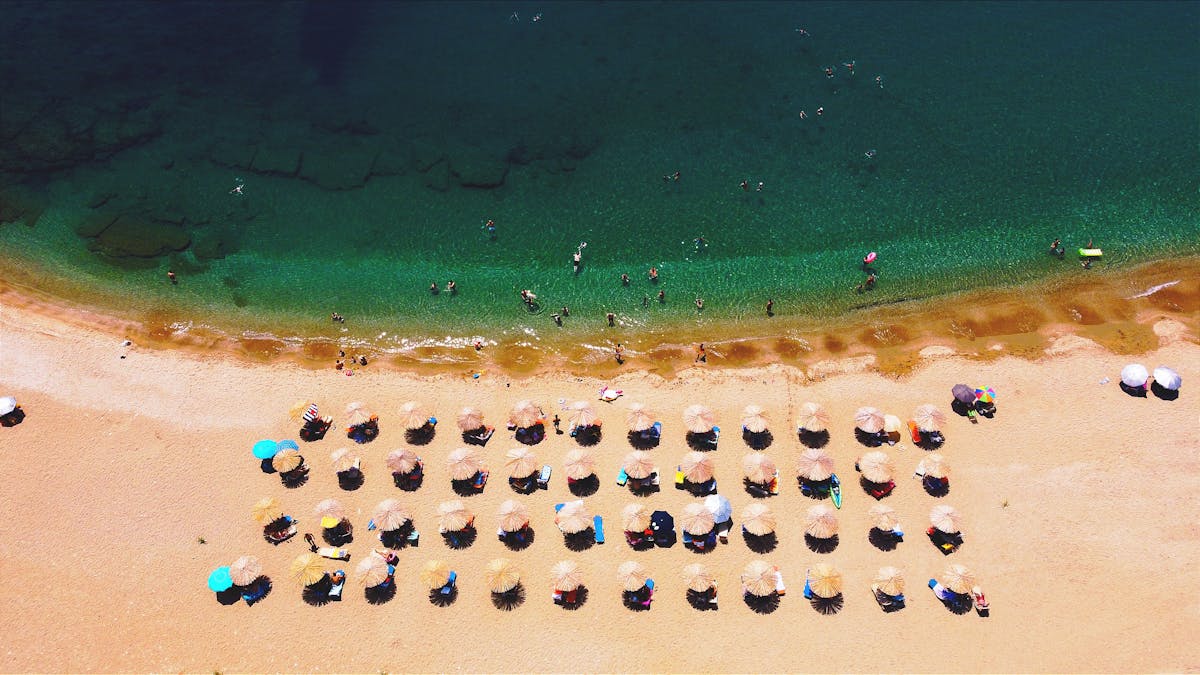 Aerial view of a Greek beach with umbrellas and swimmers