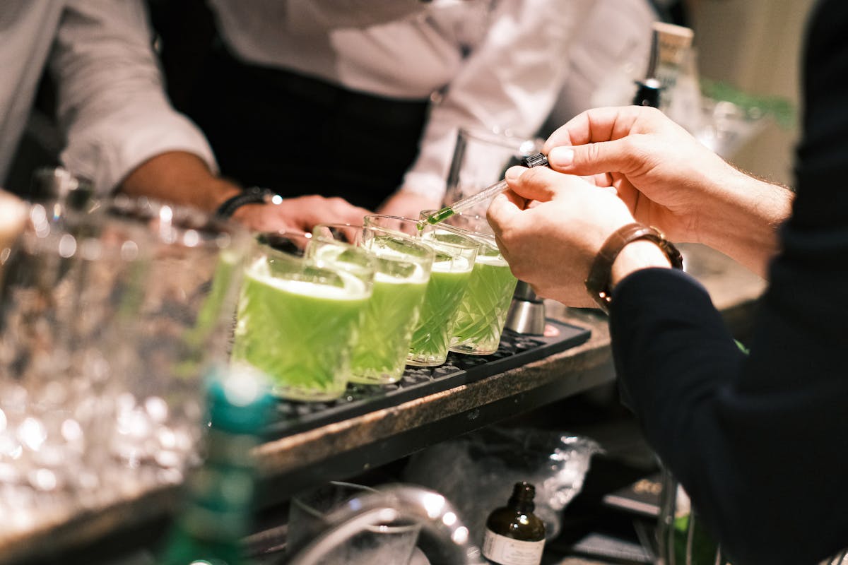 Close-up of a bartender preparing green cocktails in a stylish Parisian bar