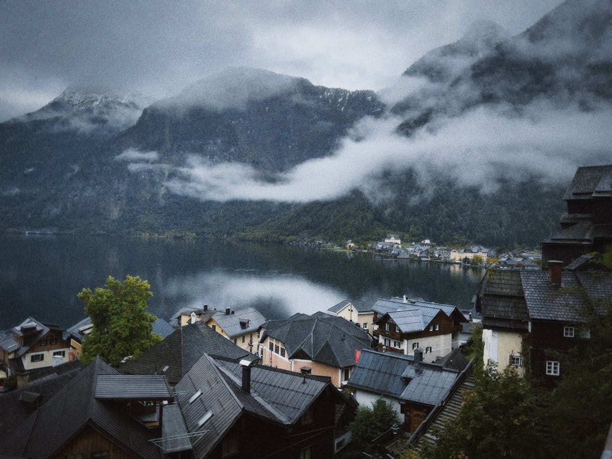 Hallstatt village with wooden houses and church tower beside the lake surrounded by misty mountains
