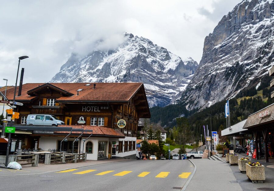 Old-style hotel building in a Swiss mountain village with snowy peaks in the fog