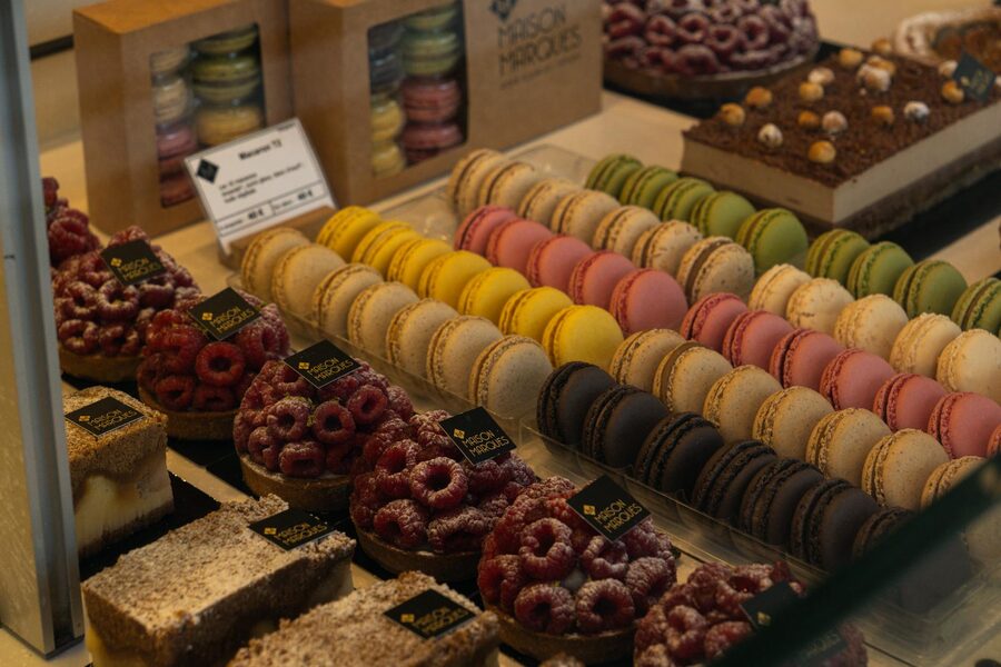 Array of colorful French macarons and pastries displayed at a patisserie