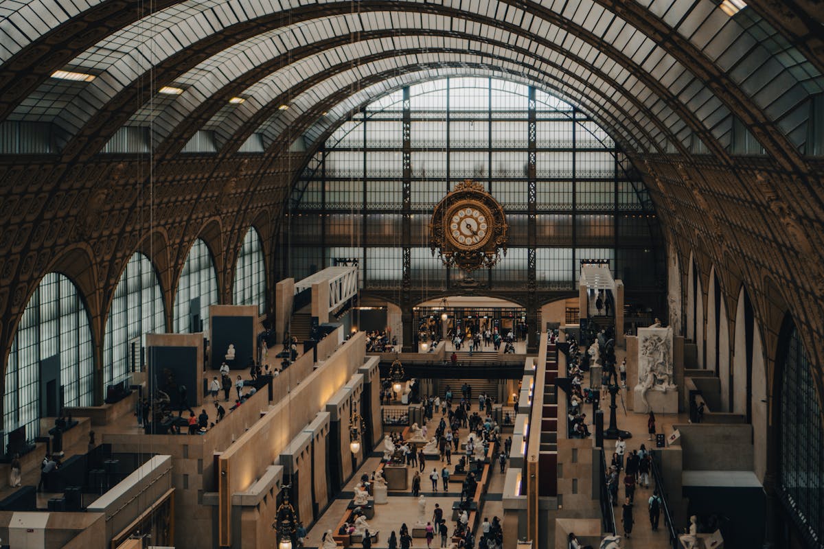 Giant ornate clock face with gallery and visitors visible through it at Musee dOrsay