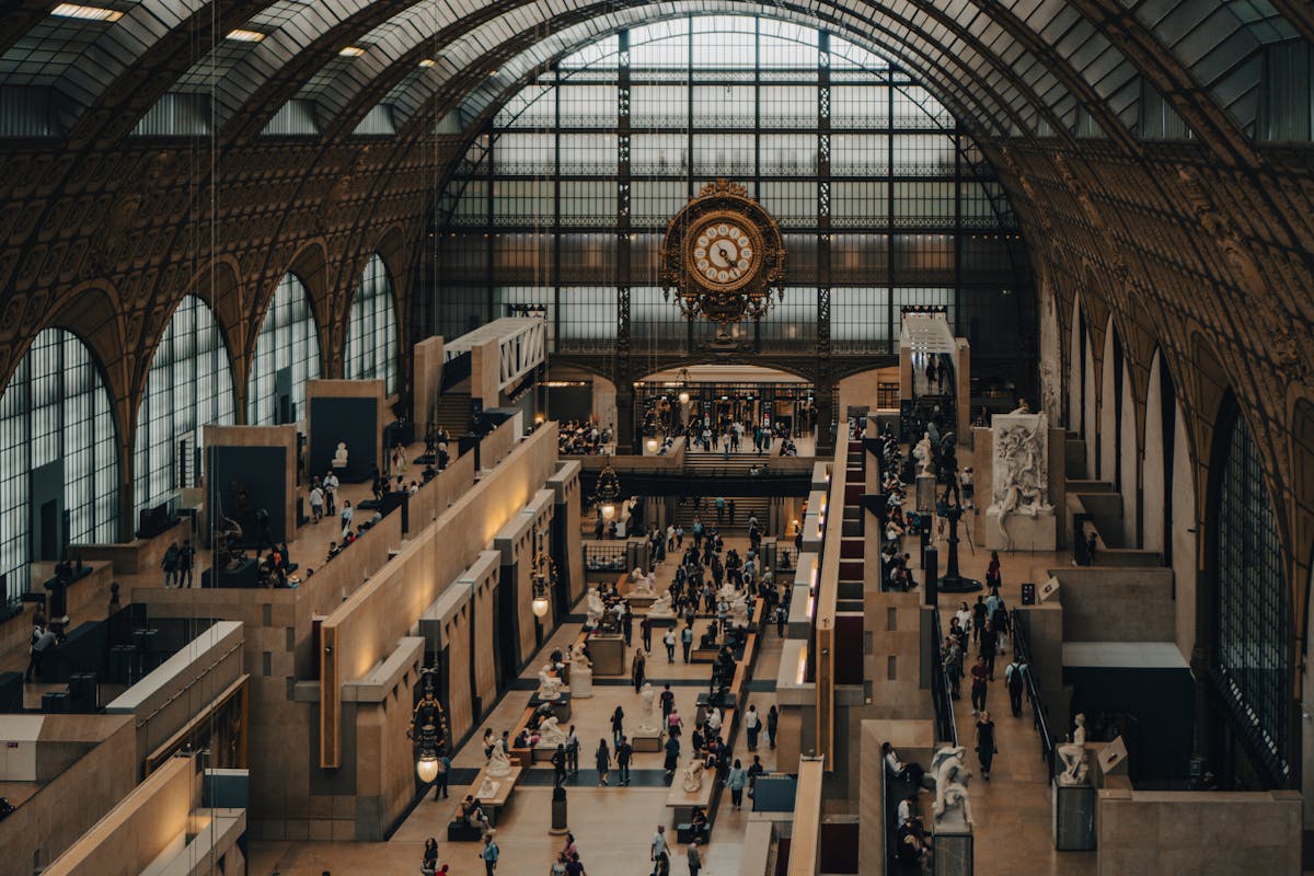 Grand interior hall of Musee dOrsay with arched ceiling sculptures and visitors