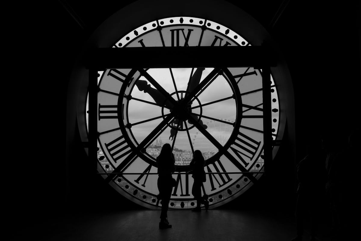 People silhouetted against the transparent clock face at Musee dOrsay with Paris visible behind