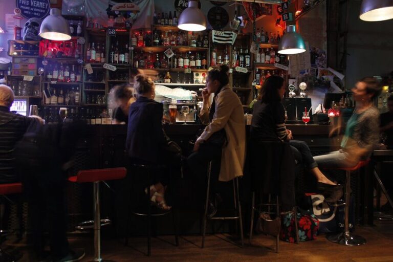 Inside a cozy Parisian bar with warm lighting and people socializing over drinks