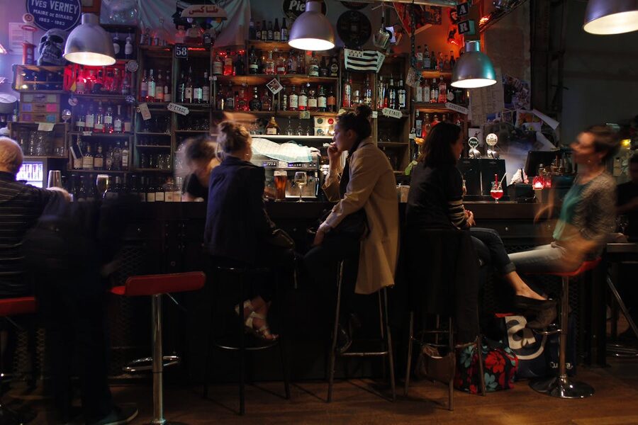 Inside a cozy Parisian bar with warm lighting and people socializing over drinks
