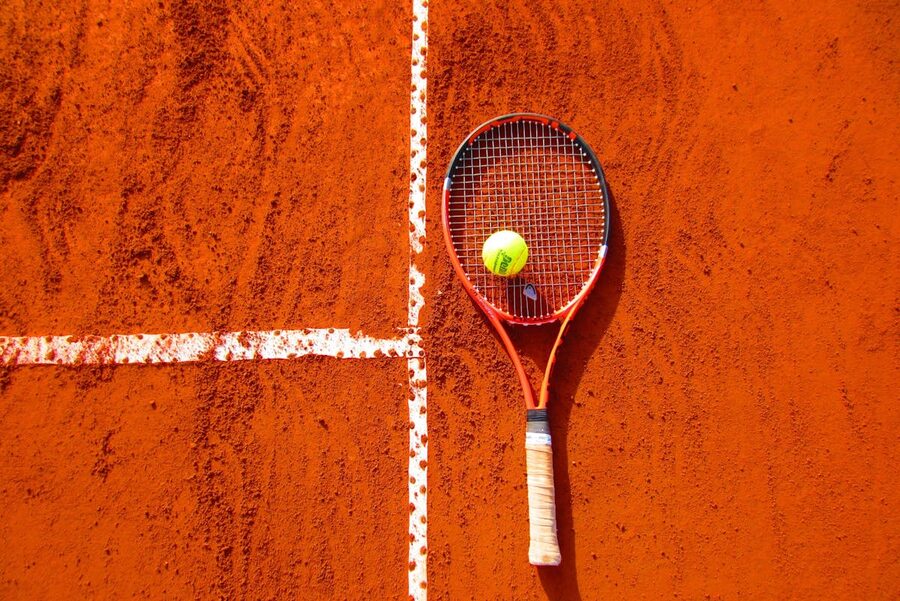 Tennis racket lying next to a tennis ball on court surface