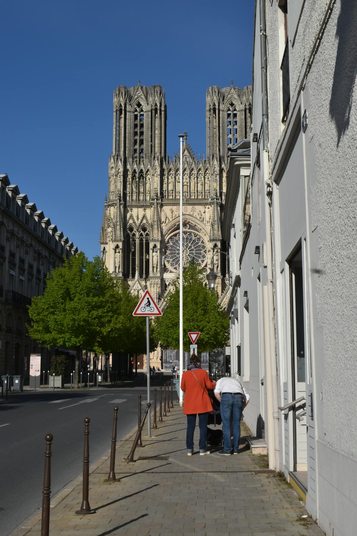 Urban street view of Reims Cathedral in France with people walking nearby