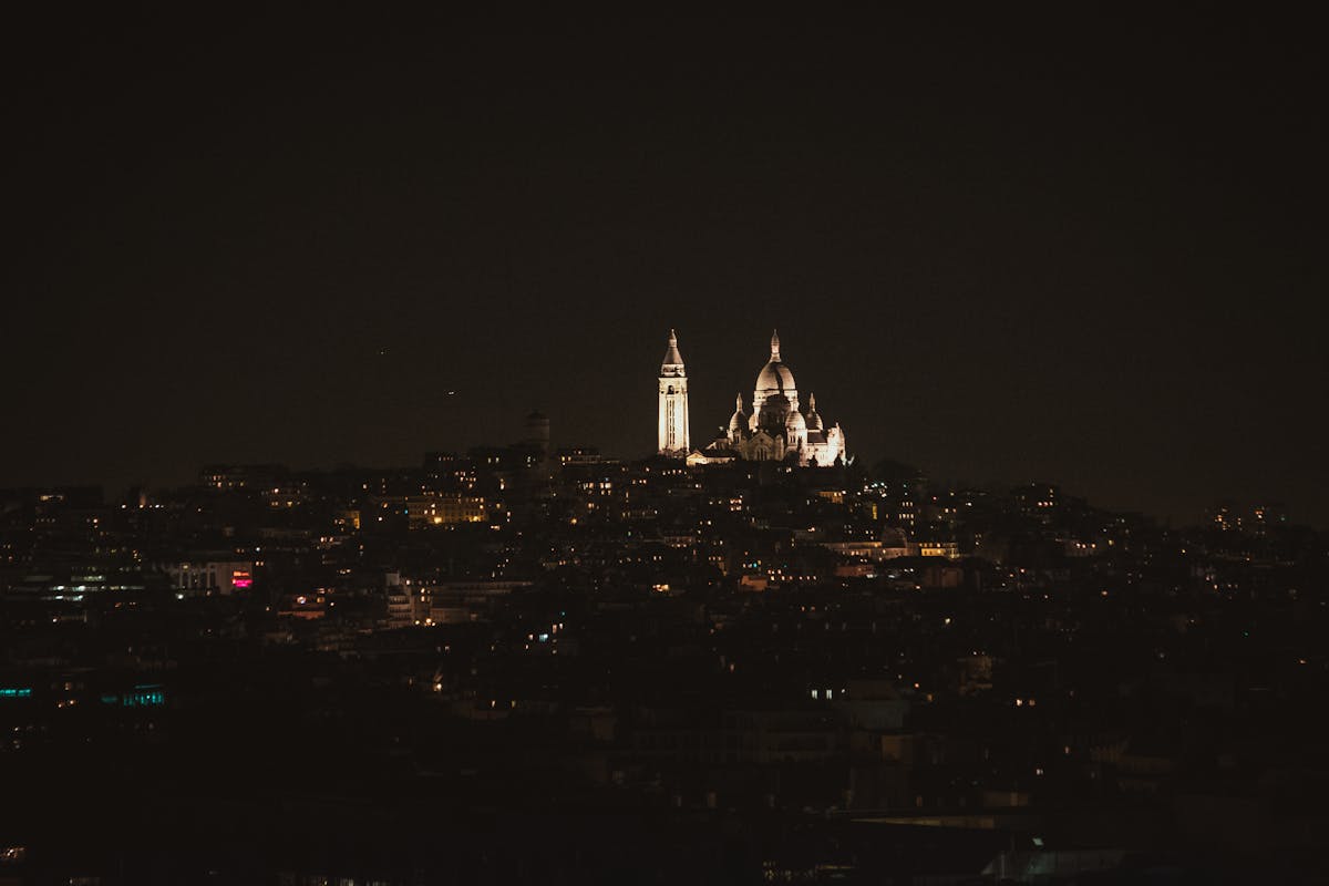 The illuminated Sacre-Coeur Basilica at night in Paris with city lights below