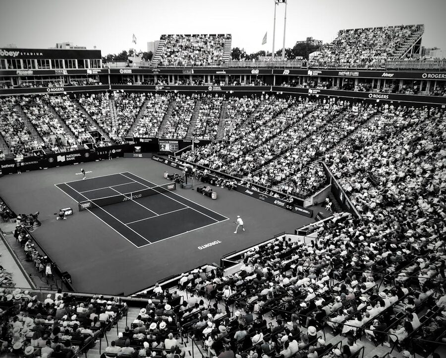 Crowded tennis stadium with spectators watching a match under lights