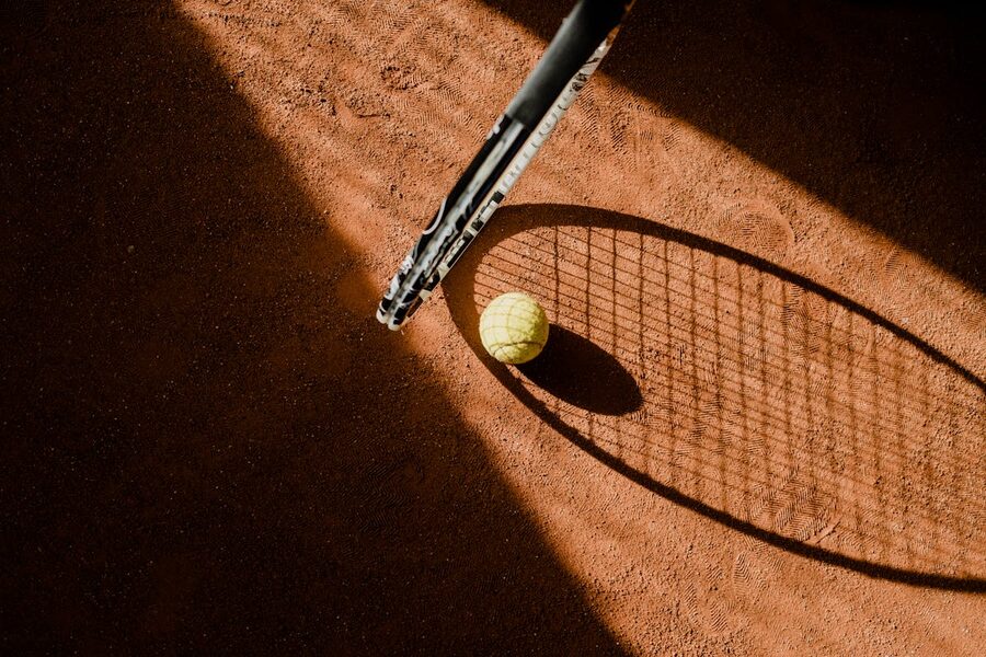 Yellow tennis ball resting on red clay court surface