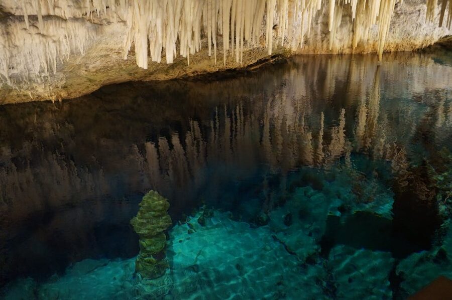 Natural underground cave featuring stalactites and crystal clear water