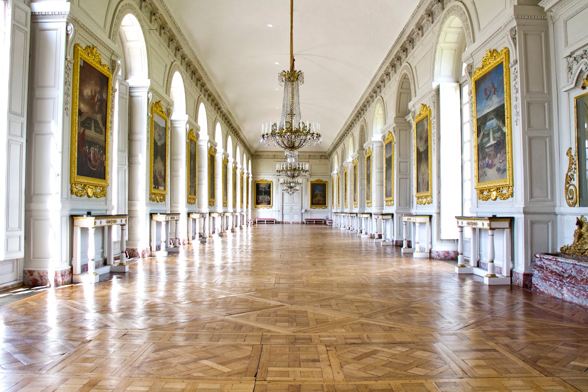 Luxurious palace hallway with chandeliers, paintings, and checkered floor at Versailles