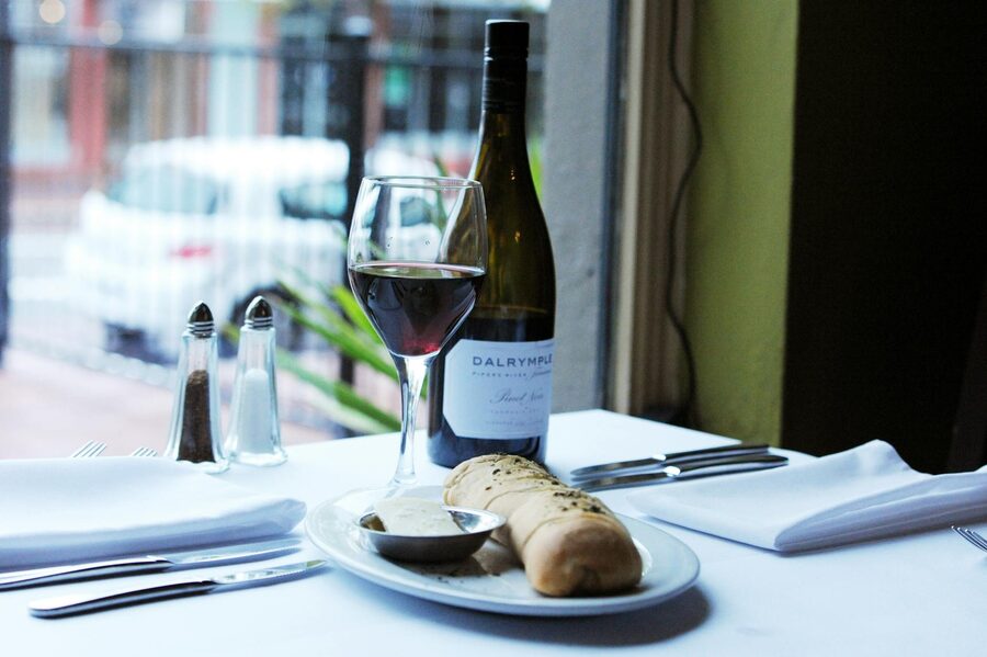 Elegant restaurant table with wine glasses, bread basket and condiments by a window